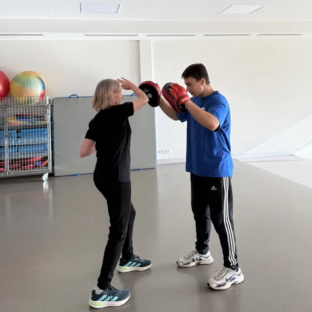 Teilnehmerin schl&auml;gt auf Handpratzen, gehalten von einem Trainingspartner