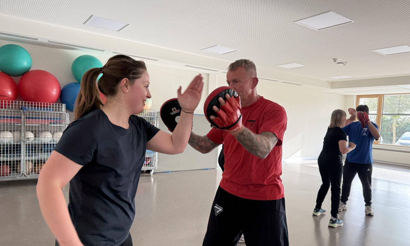 Mitarbeiterin der BG Klinik Ludwigshafen schl&auml;gt beim Firmenkurs auf die Handpratzen eines Trainers